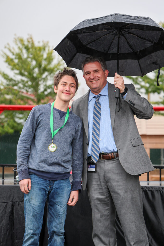Dr. Mendiburu stands holding an umbrella with 8th grade student Seth Bass.