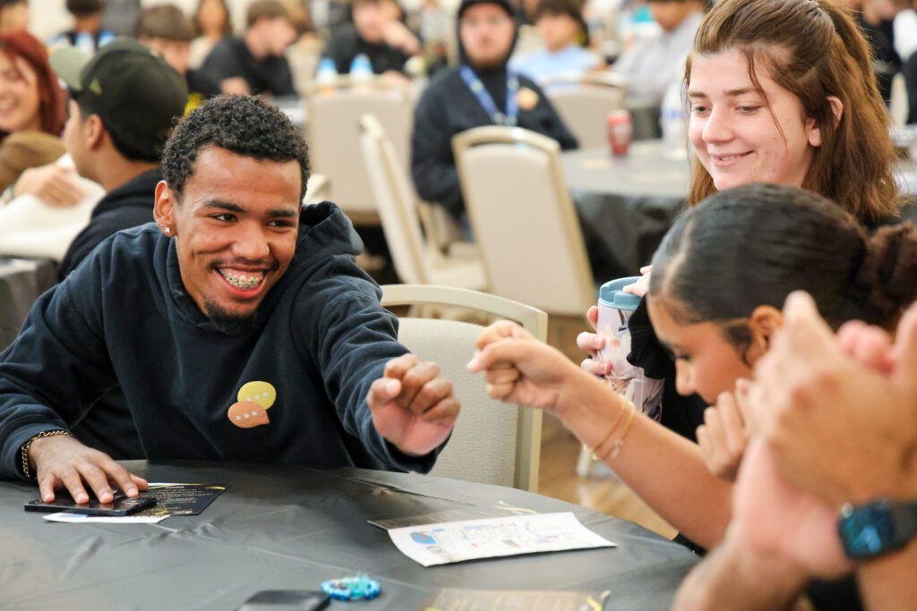 alt= "Students fist bumping after presenting."