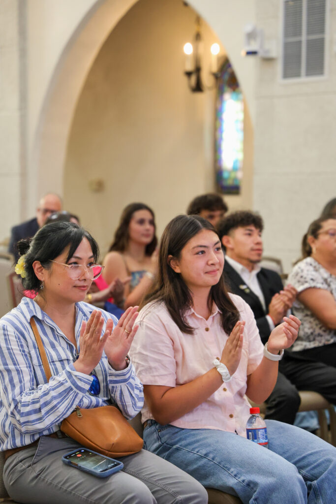 Guest in the audience applaud students.