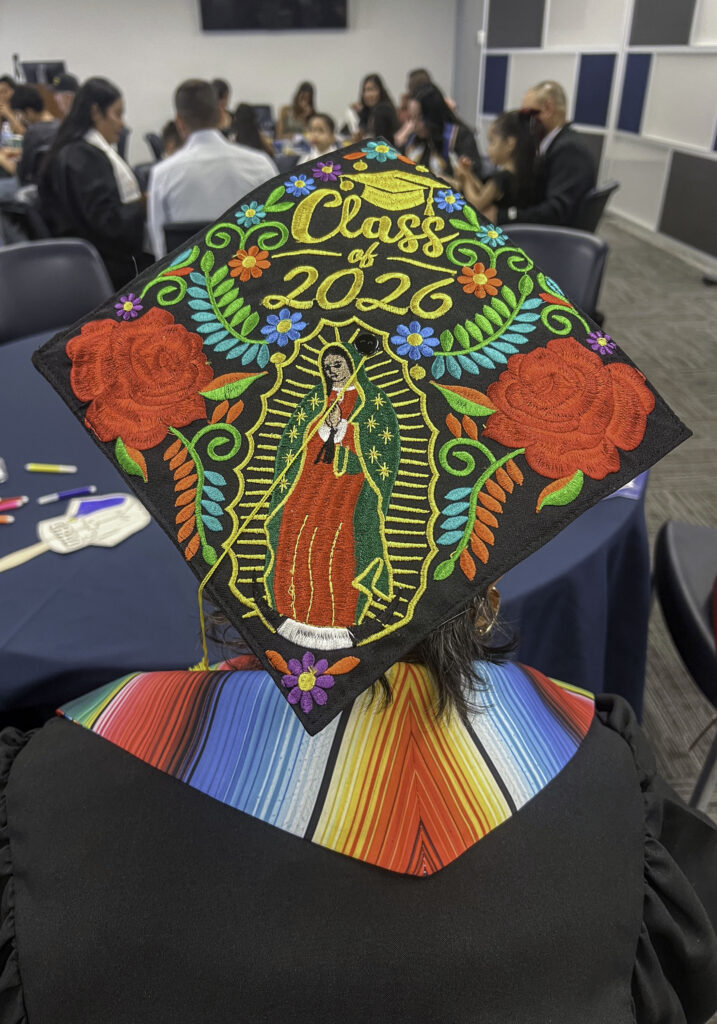 photo of a decorated mortarboard with "class of 2026" flowers, leaves and a depiction of the Virgin Mary.