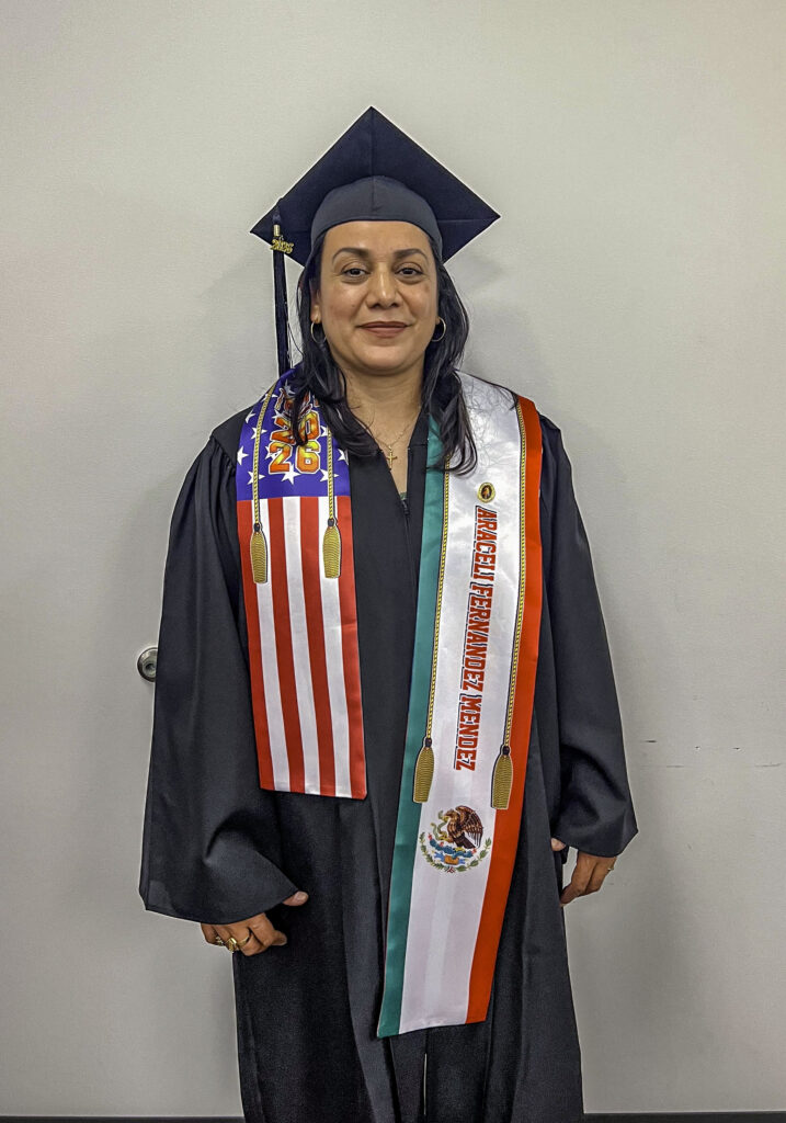 photo of a graduate posing in her cap and gown wearing a decorative sash.