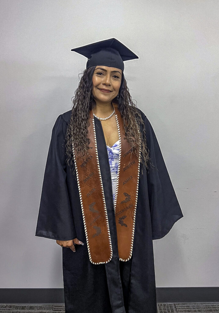 photo of a graduate posing in her cap and gown wearing a decorative sash.