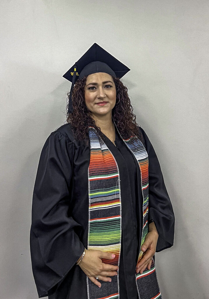 photo of a graduate posing in her cap and gown wearing a decorative sash.