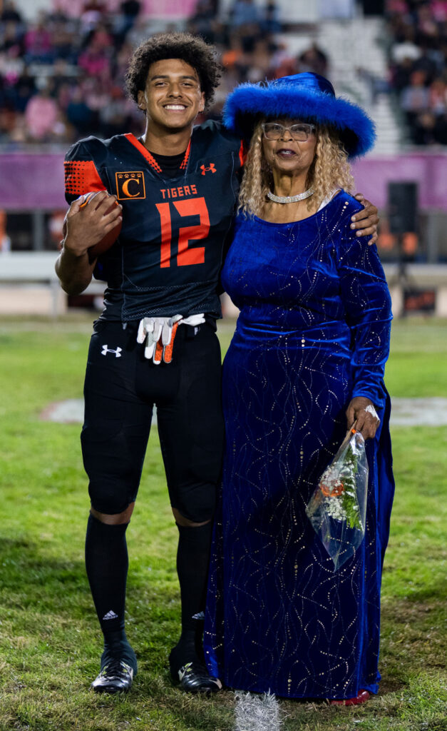 Braydon Ricks stands on the football field with his grandmother who he knows only as "mom."