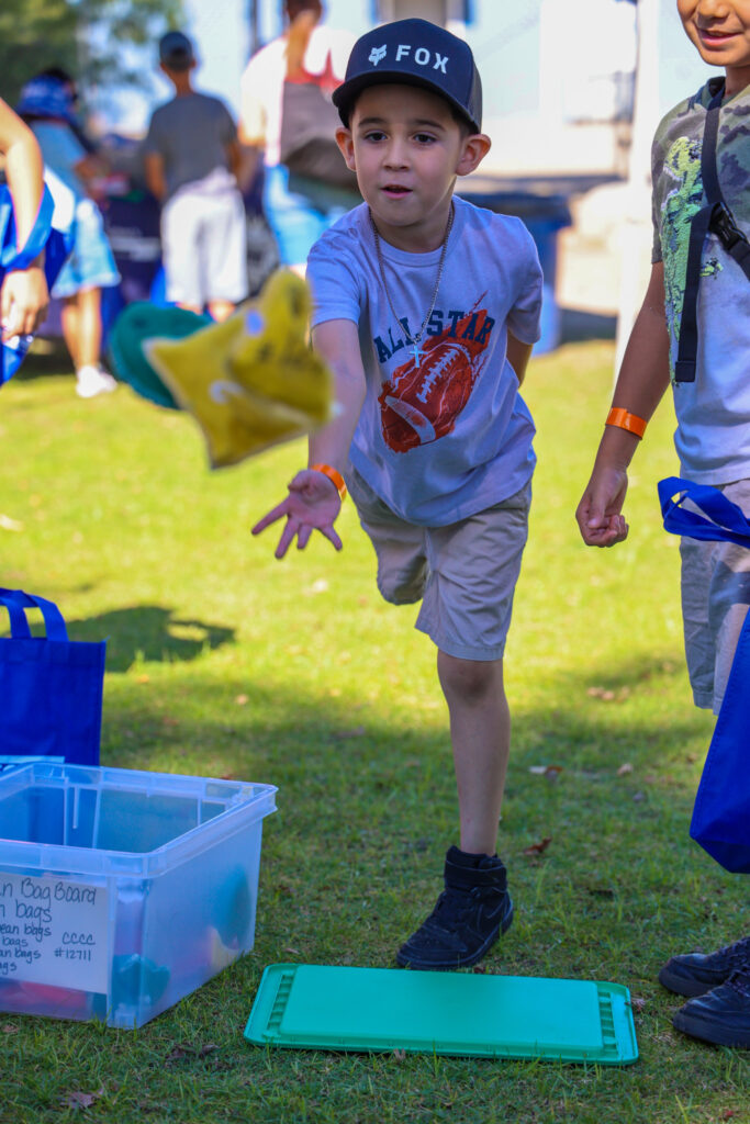 A boy throws a bean bag.