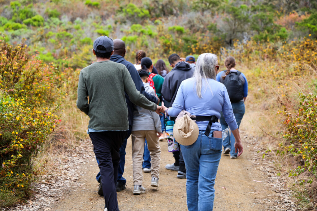 Staff and student holding hands as they hike up a hill.