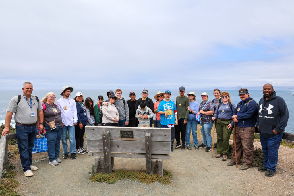 Group photo of students and staff with the ocean behind them.