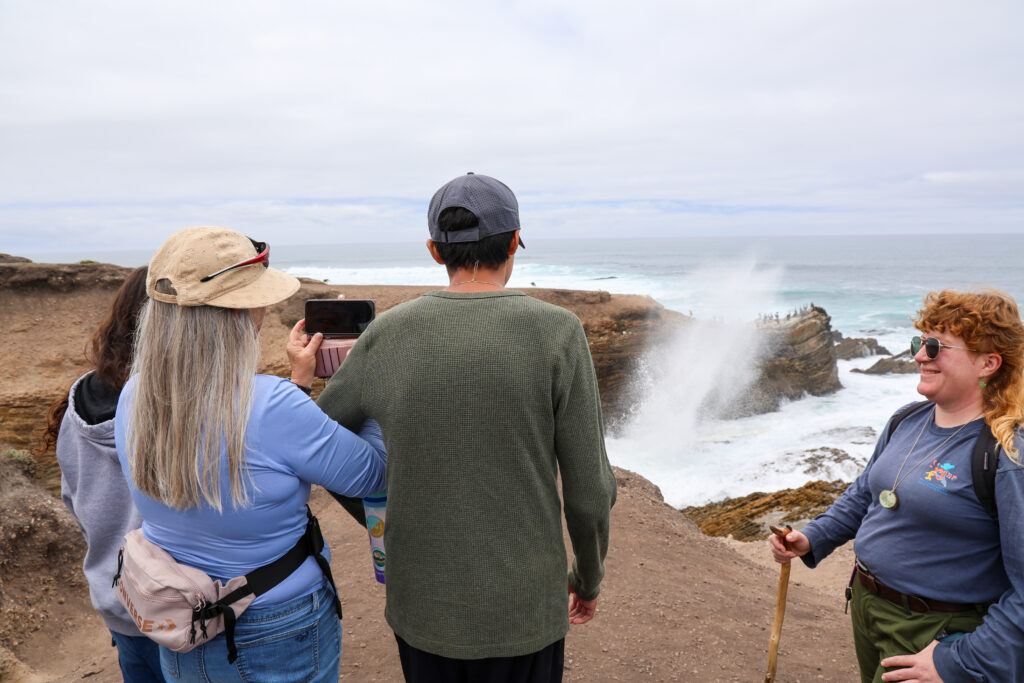 Student and staff observing a blowhole in the ocean.