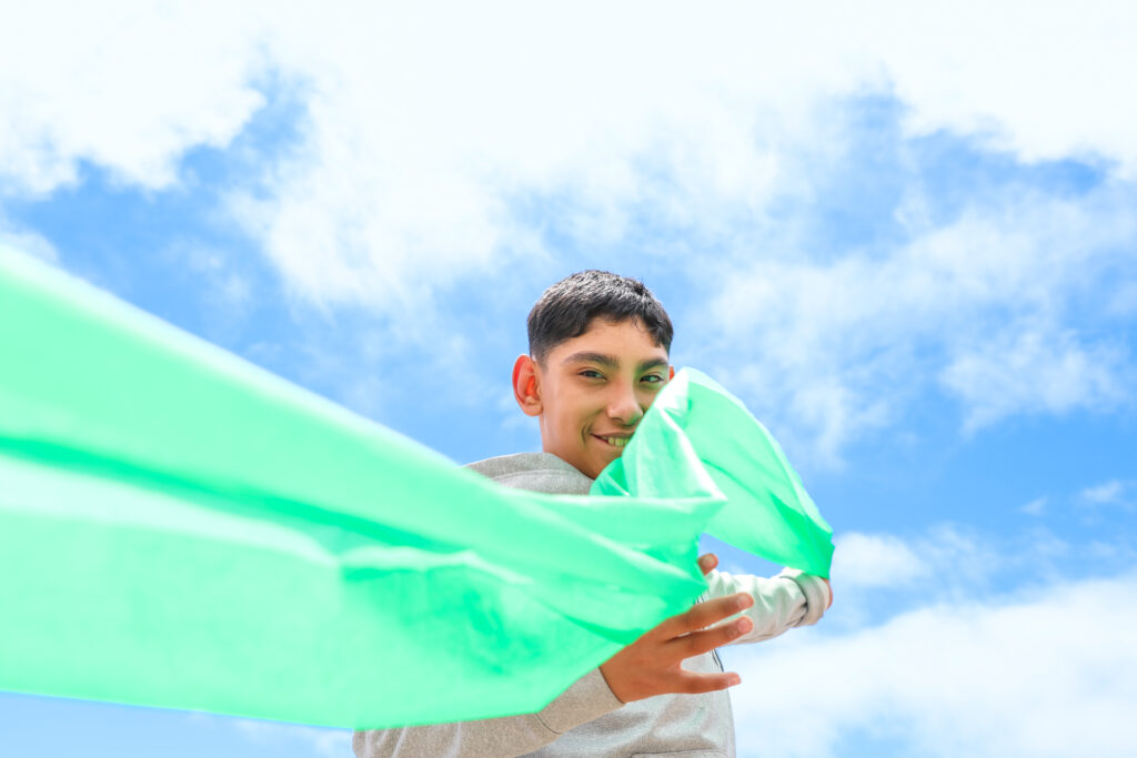Student waving a green sheet in the air like a kite.