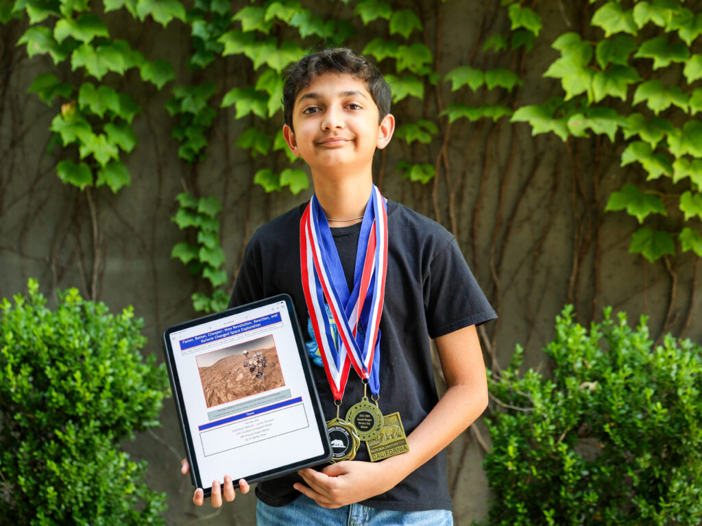 Jain wearing all three History Day competition medals and showcasing his website.