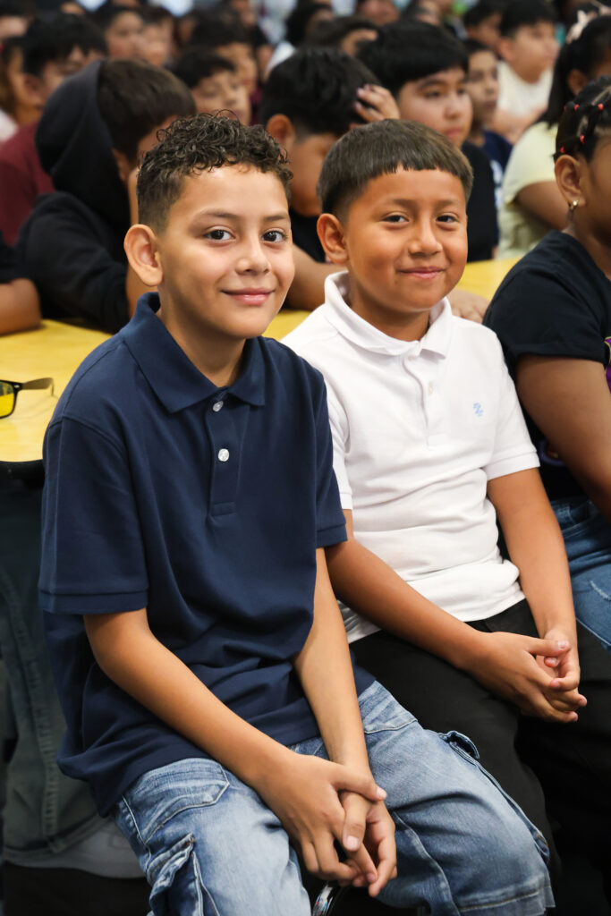 Two male students smiling directly at the camera during the school assembly.