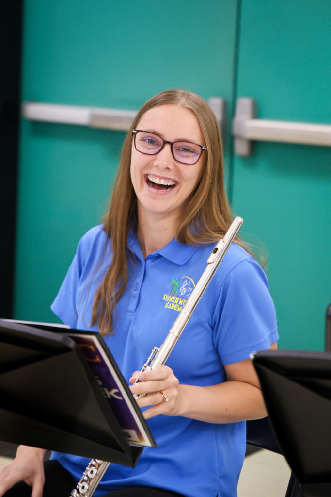 Downtown Elementary School's female music teacher wearing a district branded blue polo smiling and holding her flute.