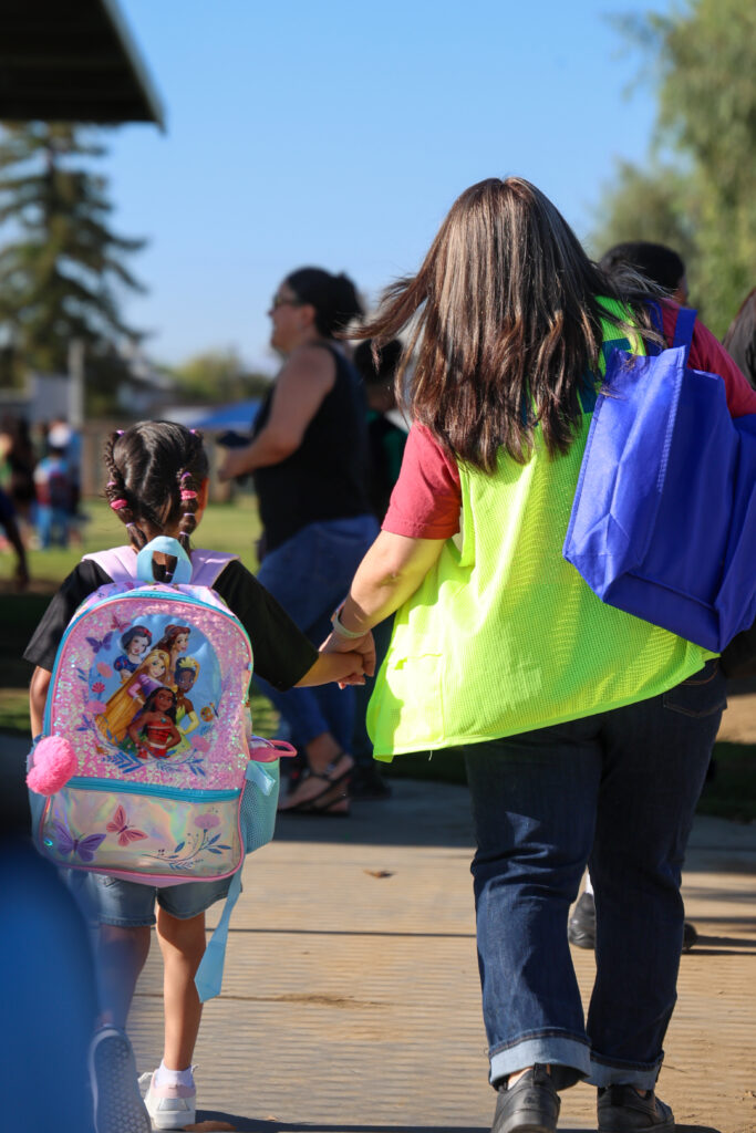 Photo of staff member walking with student on the first day of school.