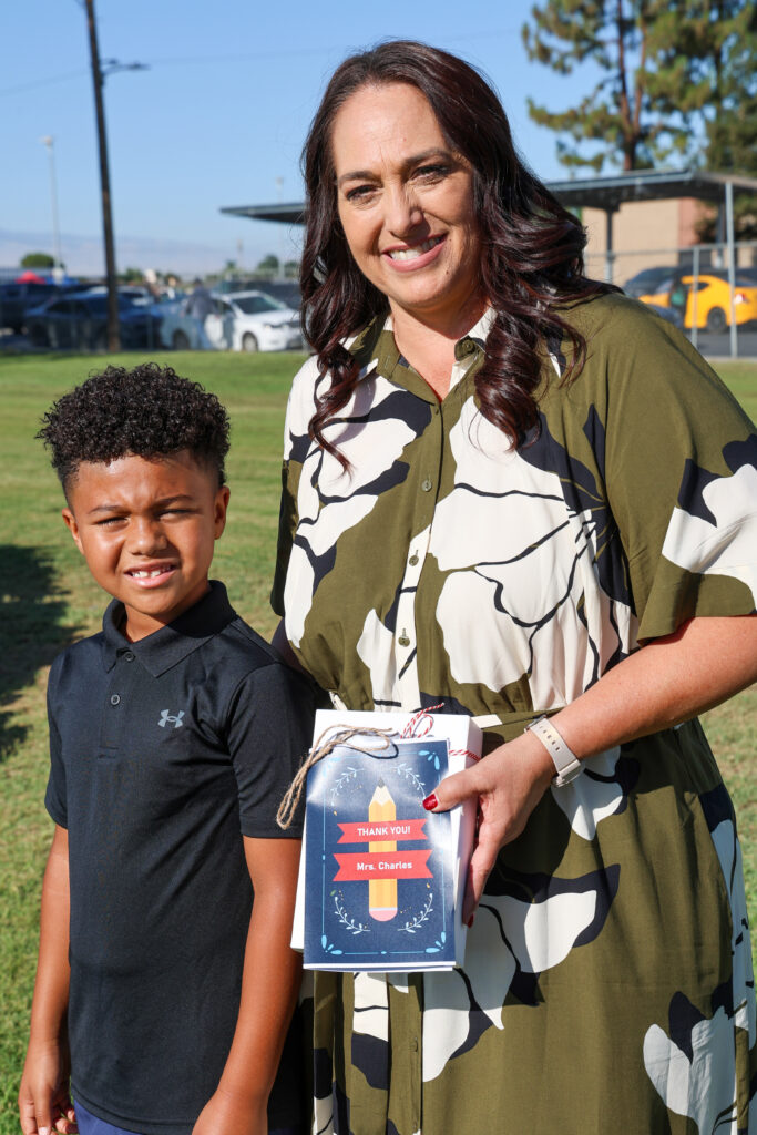 Photo of Superintendent Charles smiling with a student on the first day of school.